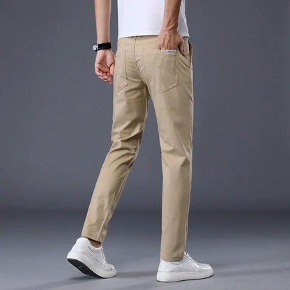 Man wearing slim fit khaki cotton dress pants with white sneakers and t-shirt, rear three-quarter view