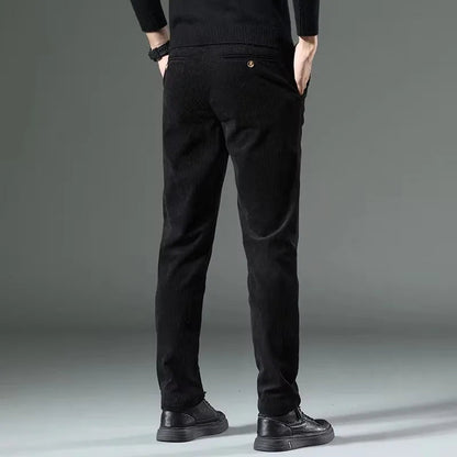 Black corduroy slim fit chino pants worn by male model, rear view, paired with black sweater and shoes