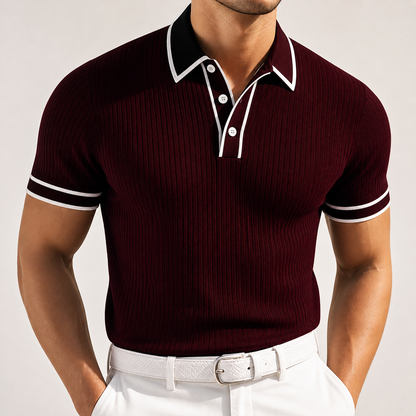 Men's burgundy ribbed knit polo shirt with black collar, white contrast trim, and short sleeves, paired with white trousers.