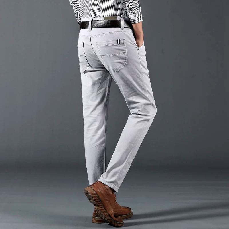 Man wearing light gray slim-fit cotton dress pants with brown leather boots and striped shirt, back view.