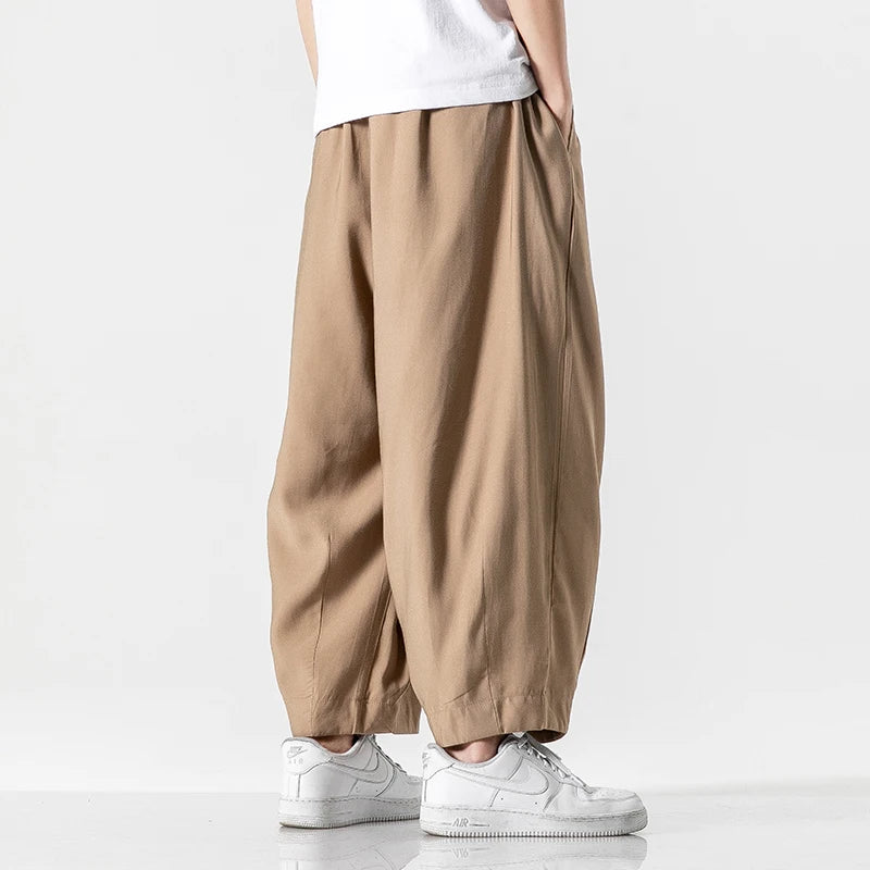 Men's khaki wide-leg cotton drawstring pants paired with white Nike Air Force 1 sneakers and white t-shirt