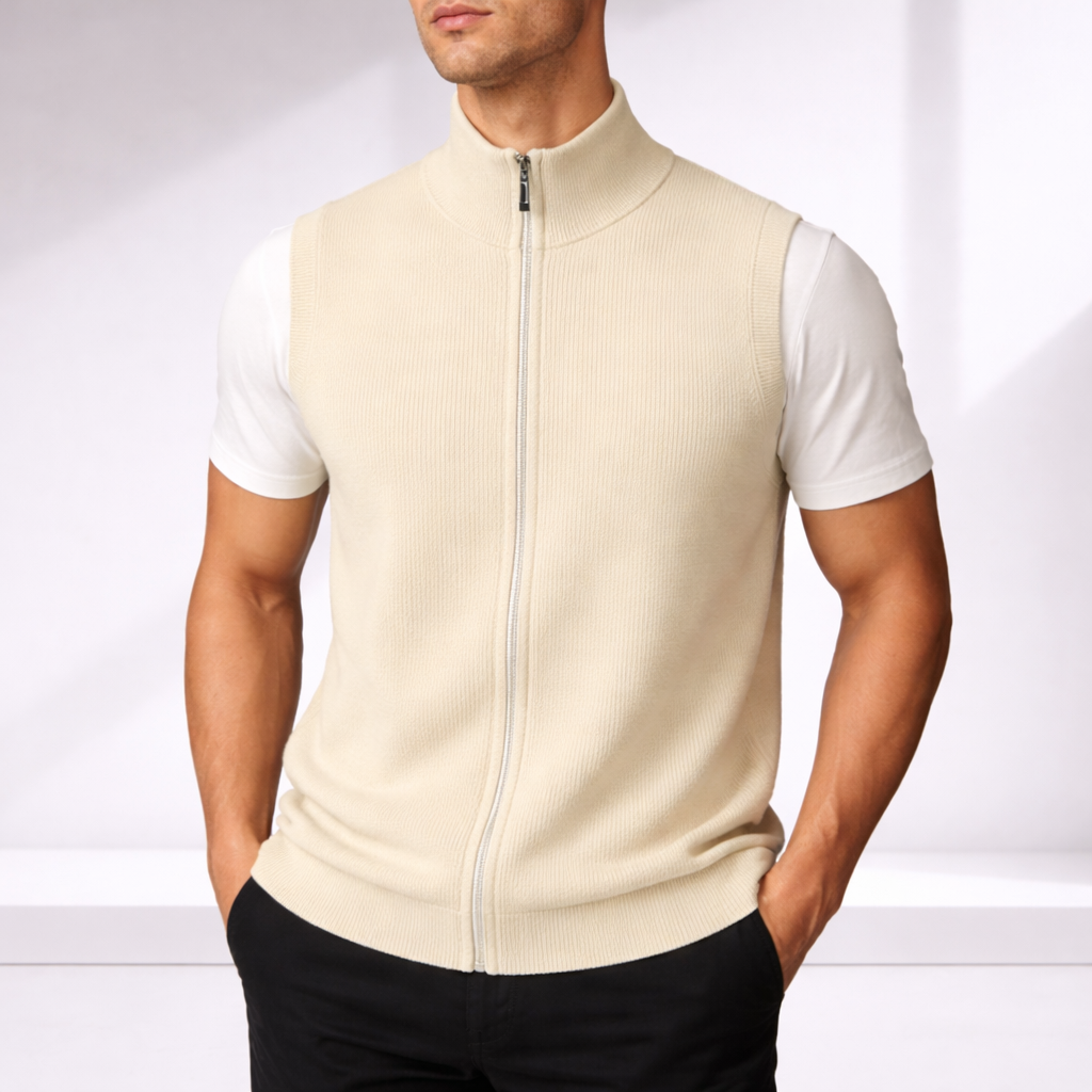 Man wearing a cream merino wool zip-up vest over a white t-shirt with black trousers, neutral background.