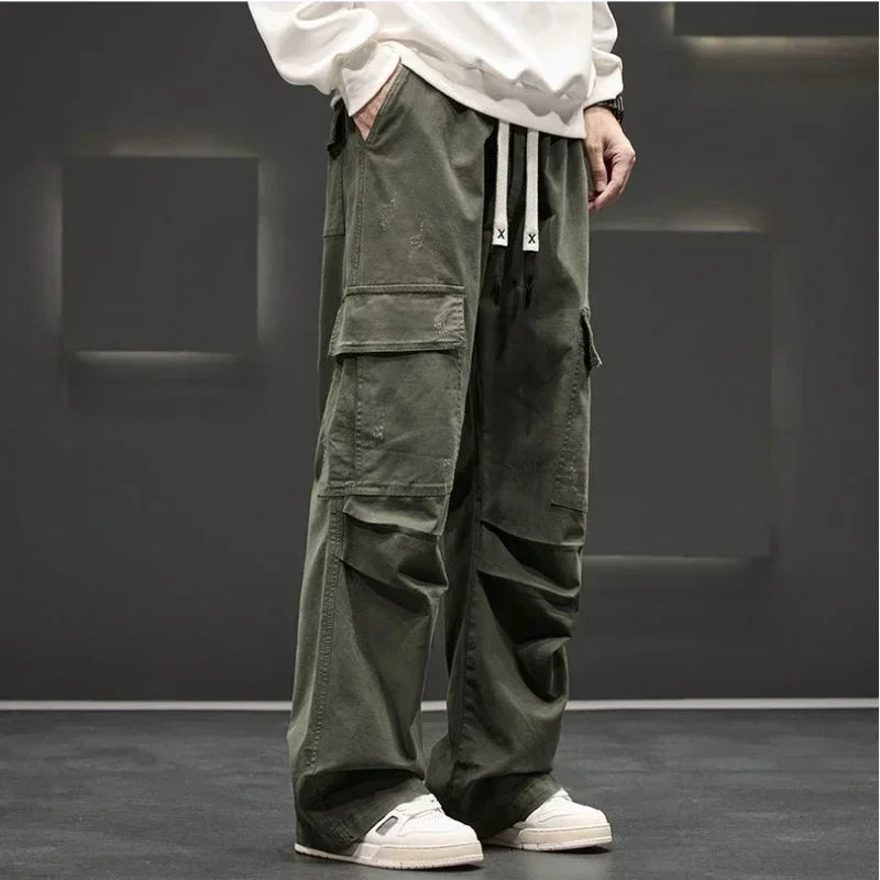 Army green wide-leg men's cargo pants with large side pockets, drawstring waist, and relaxed fit, styled with white sneakers.