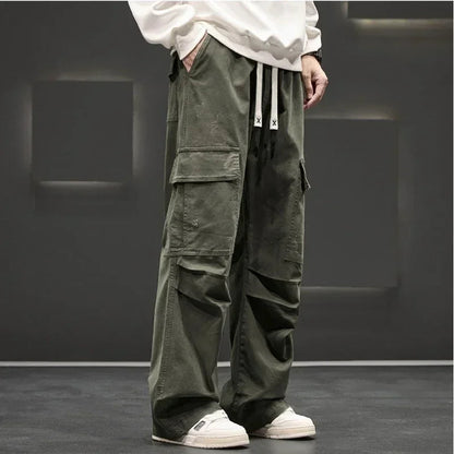 Army green wide-leg men's cargo pants with large side pockets, drawstring waist, and relaxed fit, styled with white sneakers.