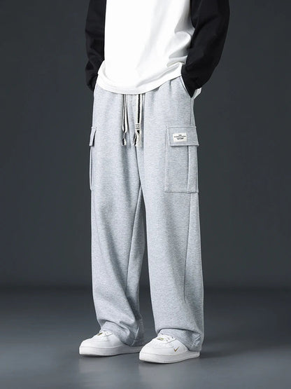 Men's light gray wide-leg cargo sweatpants with drawstring waist and patch pockets, styled with white Nike sneakers.