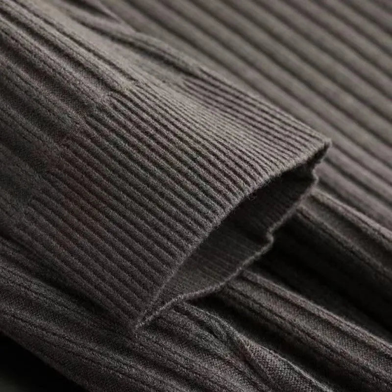 Close-up of dark brown ribbed knit fabric texture showing fine vertical ribbing detail on a men's quarter-zip sweater.