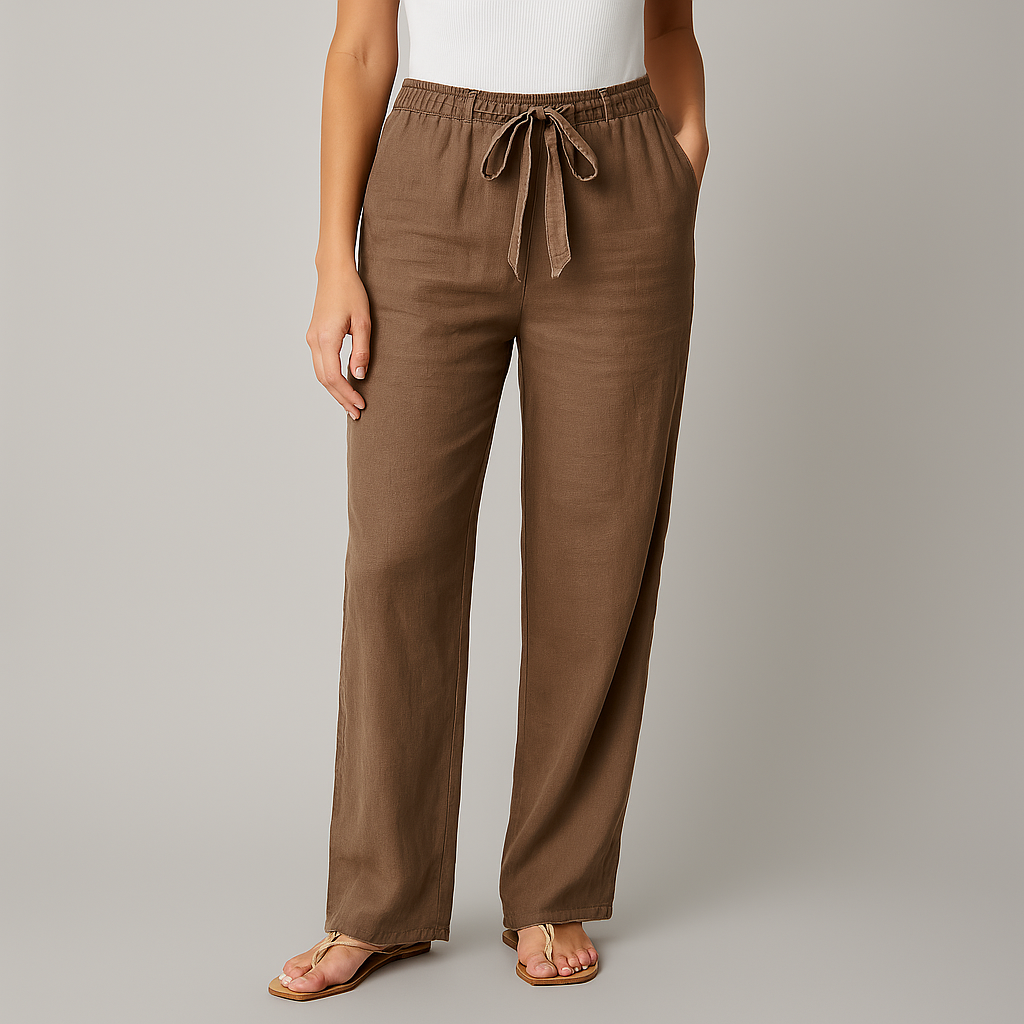 Women's brown linen wide-leg pants with elastic drawstring waist, side pockets, worn with white top and tan sandals.