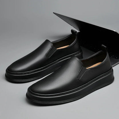 Black leather slip-on loafers for men with elastic side panels, thick rubber sole, and tan interior lining