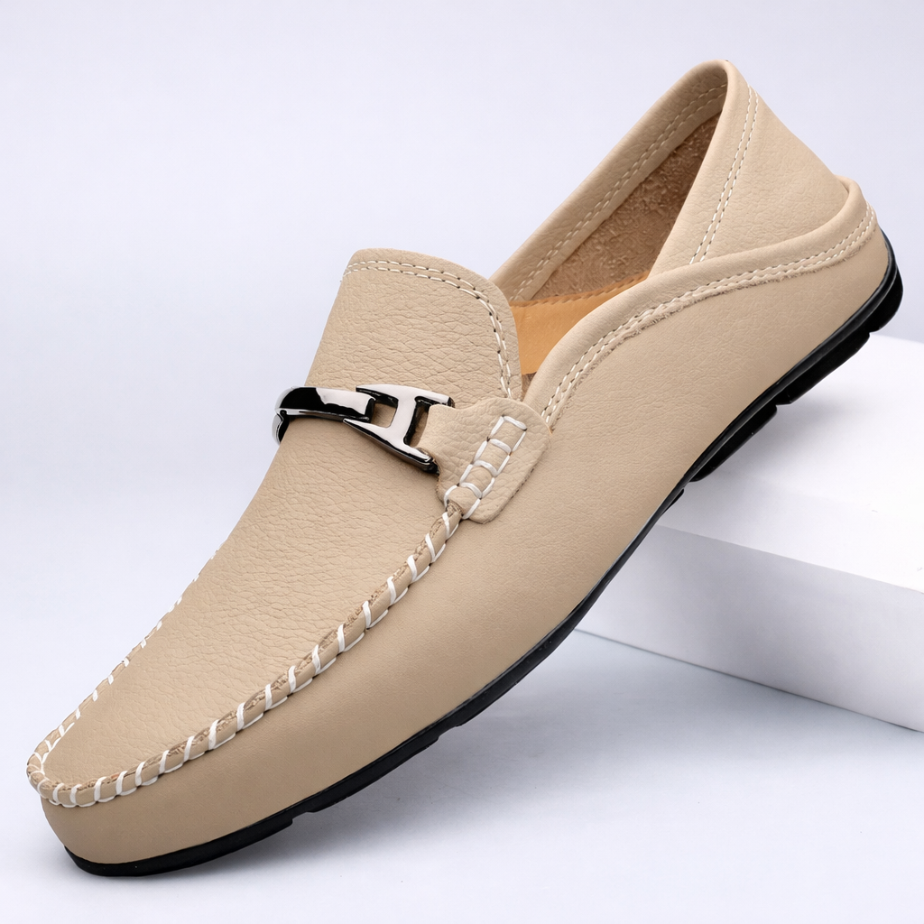Beige leather men's slip-on loafer with white contrast stitching, silver H-buckle detail, and black rubber sole.