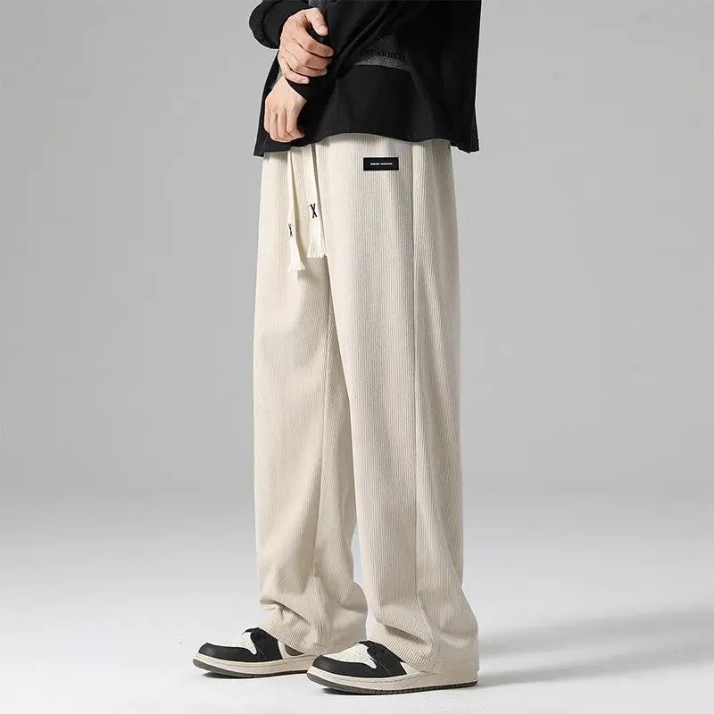 Cream corduroy wide-leg sweatpants with drawstring waist, worn with black top and black-white sneakers.