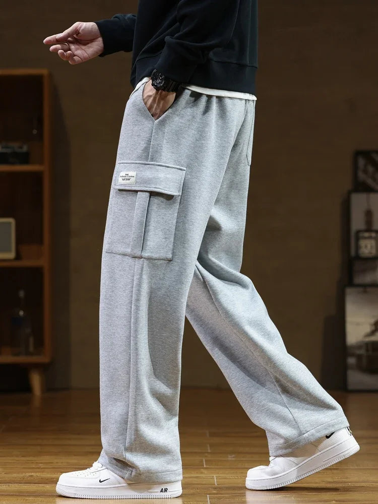 Men's gray relaxed fit cargo sweatpants with side pockets and elastic waistband worn with white sneakers