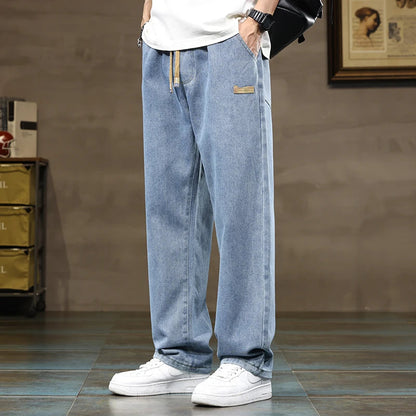 Men's wide-leg light blue drawstring denim jeans worn with white sneakers and white t-shirt, casual streetwear style