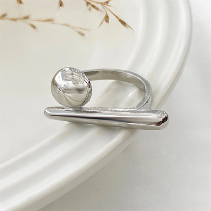 Adjustable silver-tone open ring featuring a smooth ball and horizontal bar design, displayed on white ceramic surface.