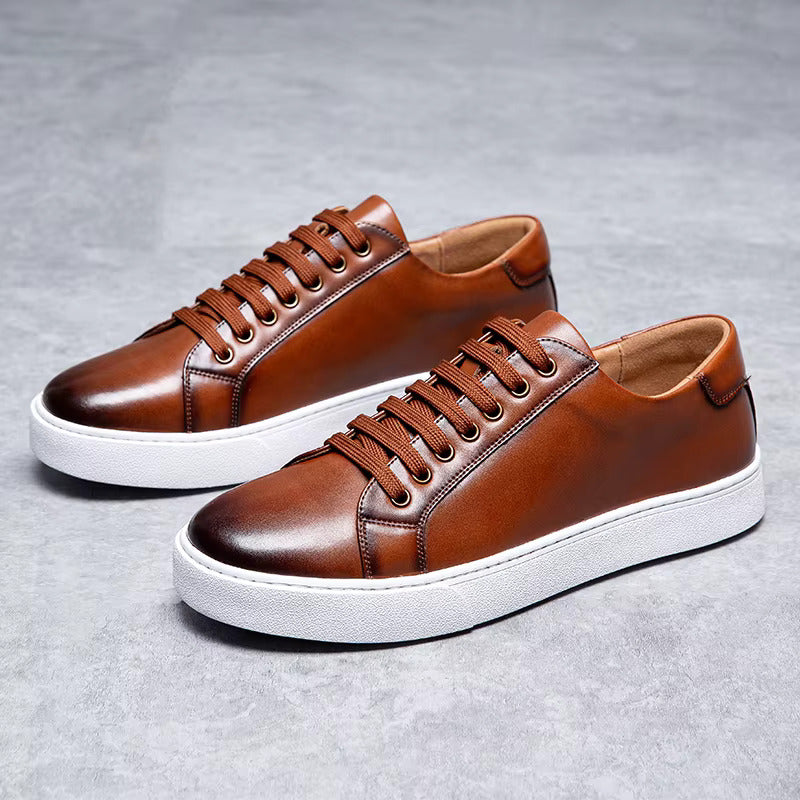 Brown leather lace-up sneakers for men with white sole and tan interior on gray background
