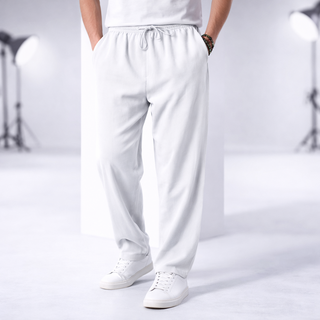Man wearing white cotton drawstring pants with side pockets and elastic waistband, paired with white sneakers.