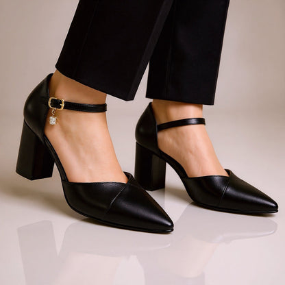 Black leather pointed-toe block heel pumps with ankle strap, gold buckle, crystal charm detail, worn with black trousers