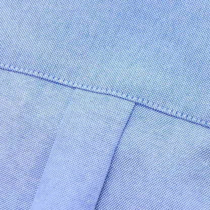 Close-up of light blue oxford cotton fabric showing fine weave texture and neat stitched seam detail on men's button-down shirt