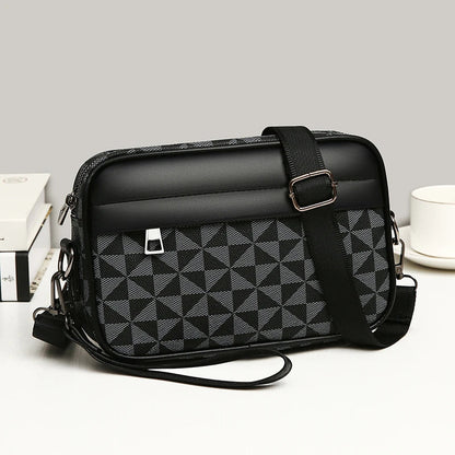 Black and gray geometric triangle pattern crossbody bag with adjustable strap, front pocket, and wrist strap handle.