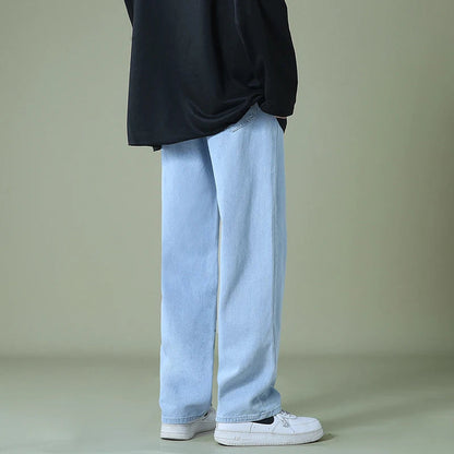Man wearing light blue relaxed-fit straight-leg denim jeans with black oversized top and white sneakers