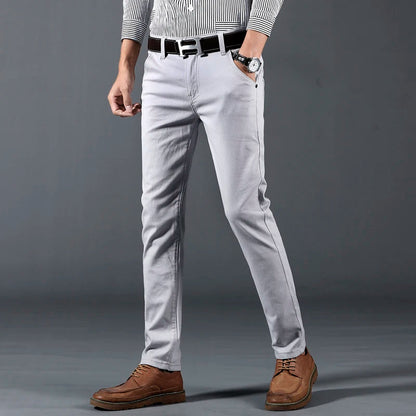 Men's slim-fit light gray cotton dress pants with black belt, paired with striped shirt and brown leather shoes.
