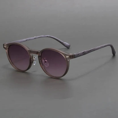 Round gray tortoiseshell acetate sunglasses with gradient purple-brown lenses and marbled temple arms on gray background