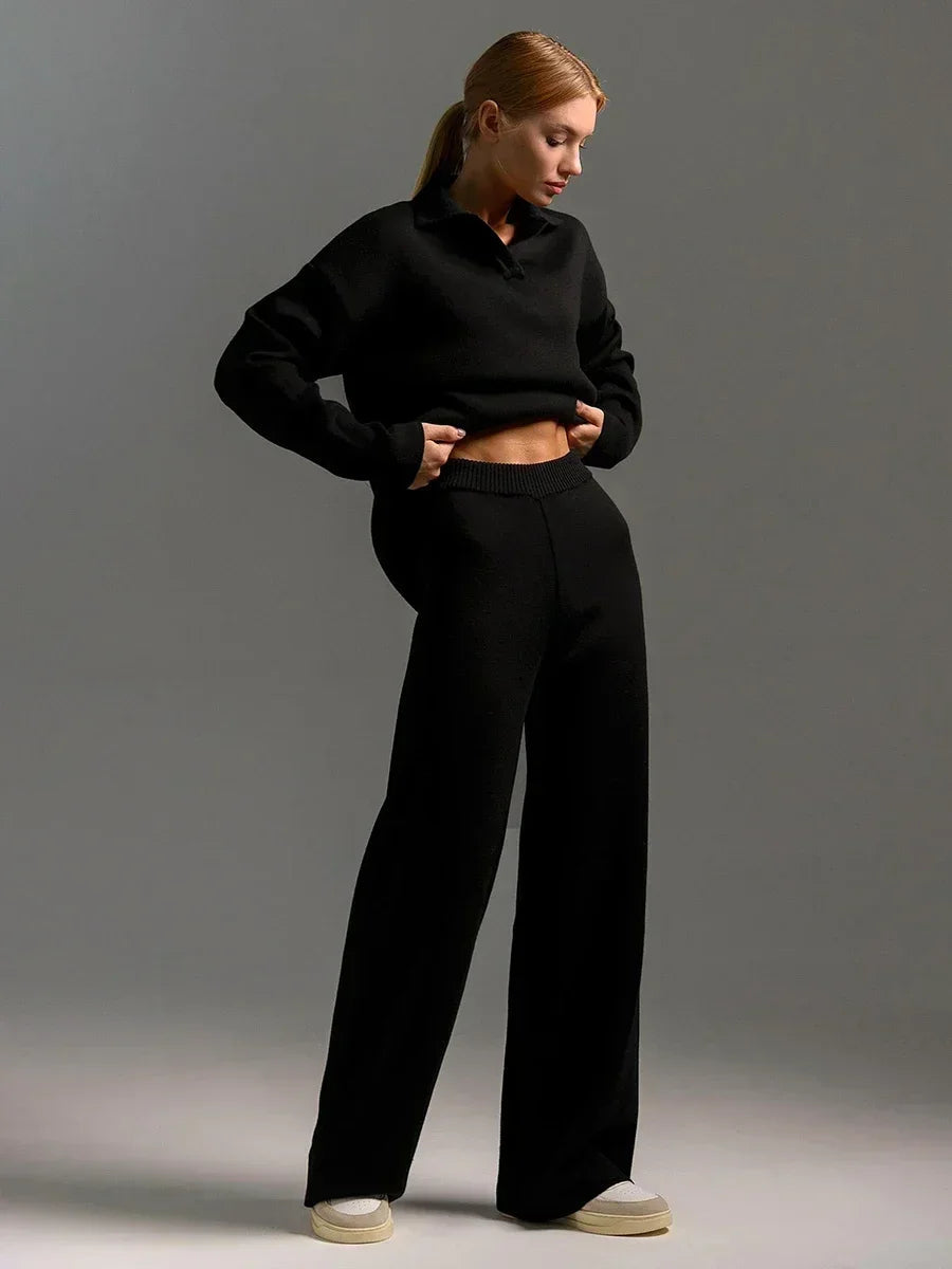 Woman wearing black collared cropped knit sweatshirt and matching wide-leg pants set with white sneakers