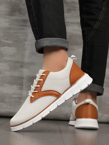 White and tan canvas leather orthopedic sneakers with lace-up closure and white sole, paired with black jeans.