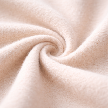 Close-up of soft cream cashmere fabric twisted into a spiral, showcasing the luxurious texture of a men's zip-up sweater jacket.