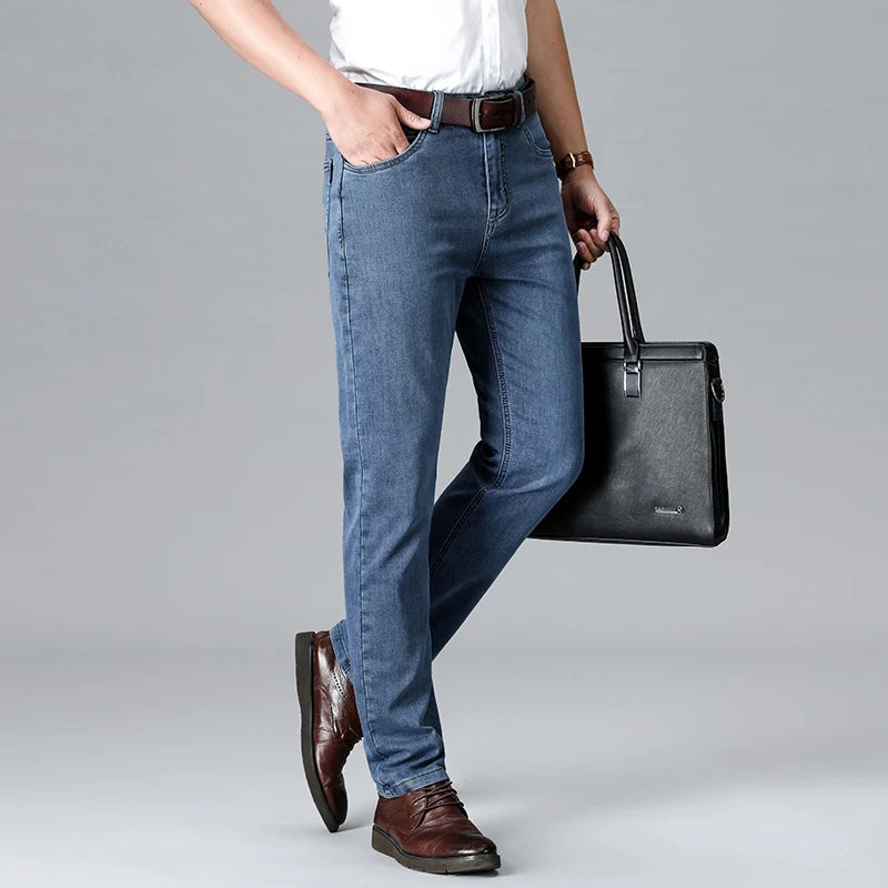 Man wearing light blue stretch slim-fit denim jeans with brown belt and shoes, holding black leather briefcase.