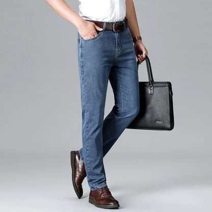Man wearing light blue stretch slim-fit denim jeans with brown belt and shoes, holding black leather briefcase.