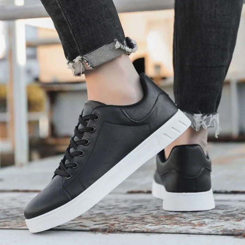 Black leather lace-up low-top sneakers with white sole, worn with distressed gray jeans, casual men's style