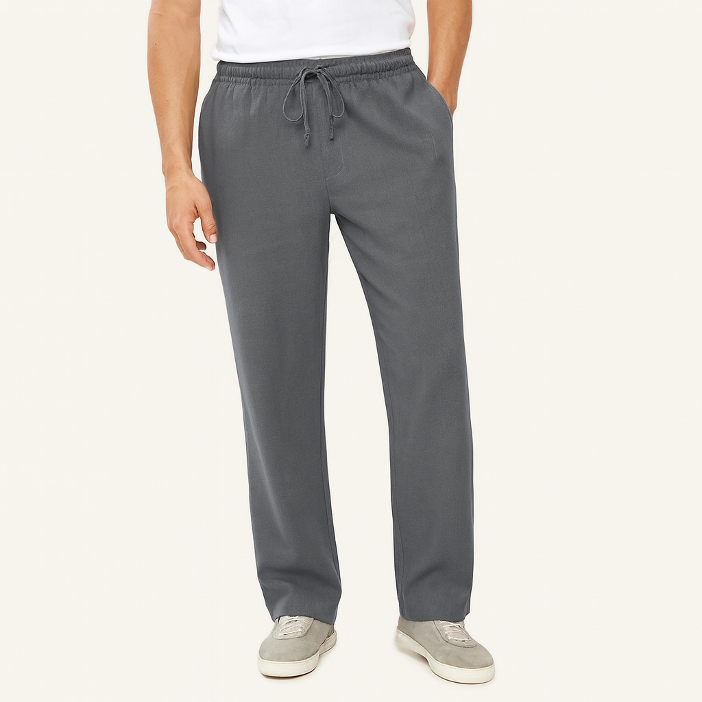 Man wearing relaxed-fit gray cotton drawstring pants with elastic waist, paired with a white tee and gray sneakers.