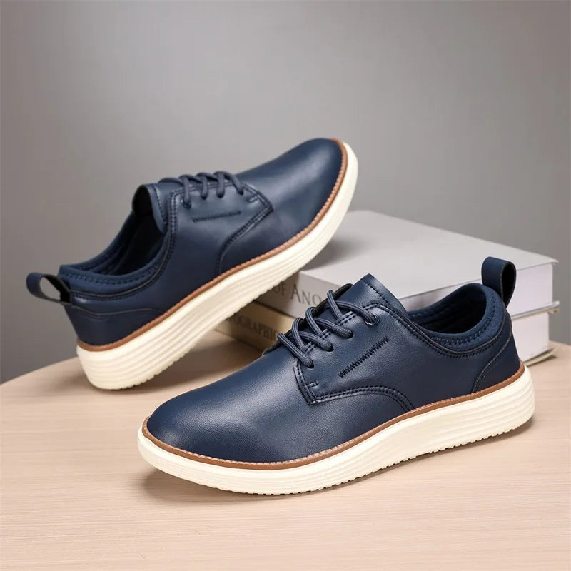 Navy blue leather lace-up casual men's shoes with white chunky sole and brown accent, displayed on wooden surface