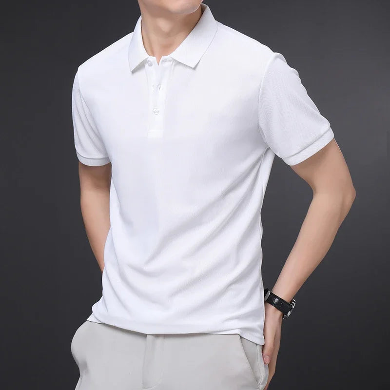 Man wearing a plain white short-sleeve cotton polo shirt with collar and buttons, paired with light gray pants.