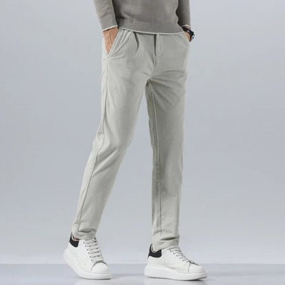 Light gray men's slim fit corduroy pants paired with a gray sweater and white sneakers, front view.