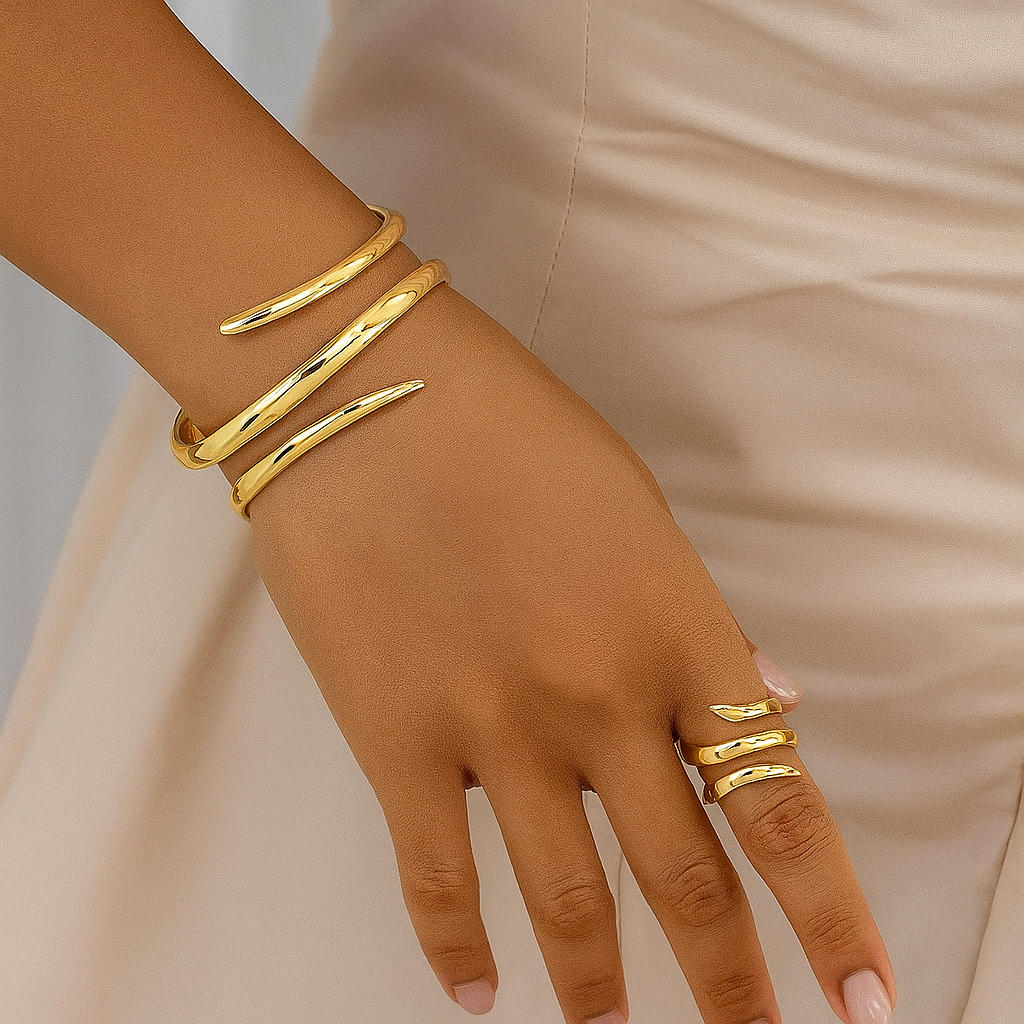 Gold-tone spiral wrap bracelet and matching ring set on woman's wrist and finger against neutral background