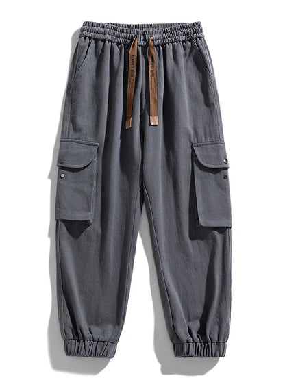 Gray men's cargo joggers with side flap pockets, elastic waistband, drawstring, and tapered cuffed ankles.