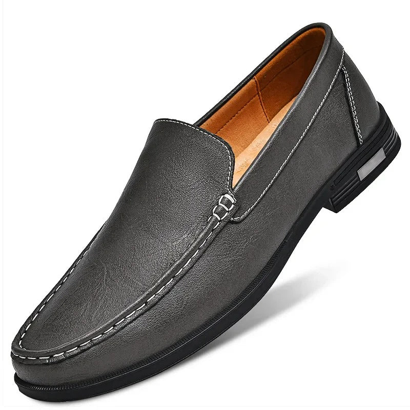 Gray men's leather slip-on loafer with contrast white stitching, tan interior lining, and black rubber sole.