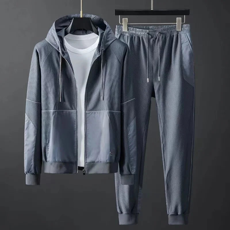 Men's gray hooded tracksuit set with mesh panels, zip-up jacket and matching jogger pants on hanger