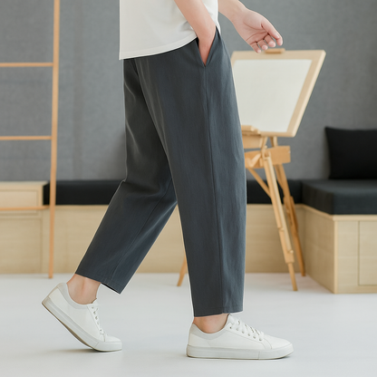 Man wearing dark gray tapered linen-cotton pants with white sneakers and white t-shirt, cropped ankle length fit.