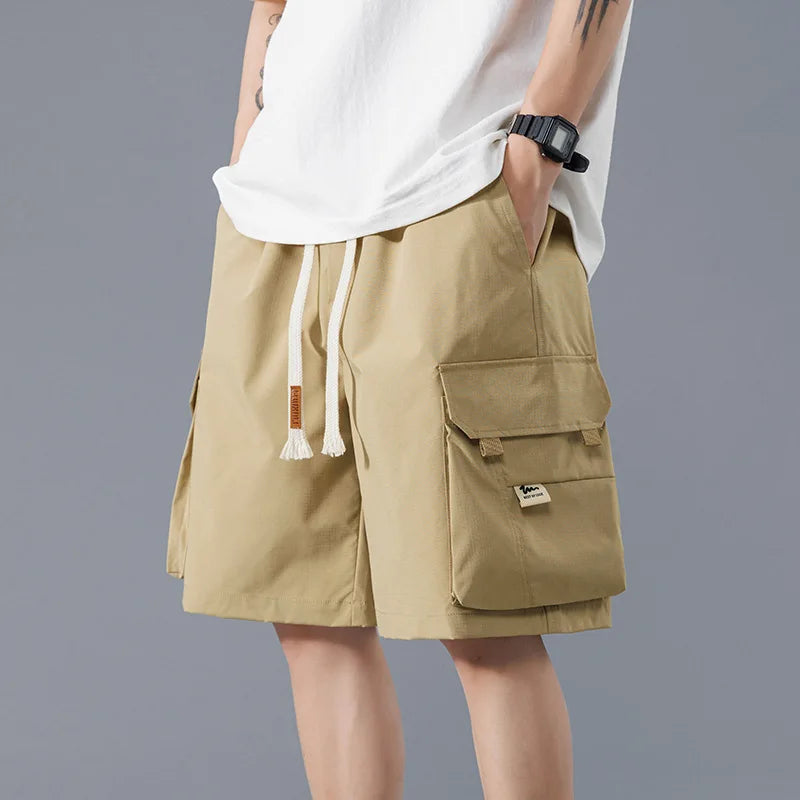 Men's beige cargo shorts with drawstring waist and utility pockets, casual streetwear style