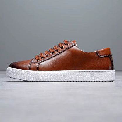 Brown leather lace-up sneakers for men with white sole and orange laces on gray background