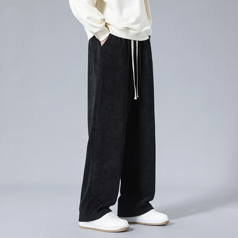 Men's black wide-leg corduroy drawstring sweatpants styled with a cream sweatshirt and white sneakers