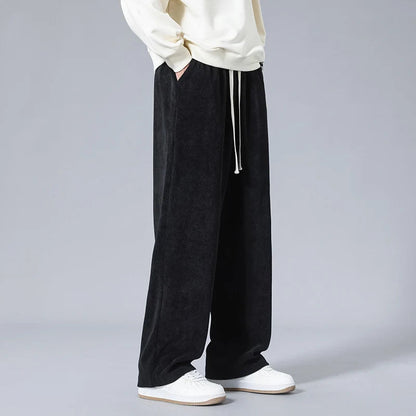 Men's black wide-leg corduroy drawstring sweatpants styled with a cream sweatshirt and white sneakers