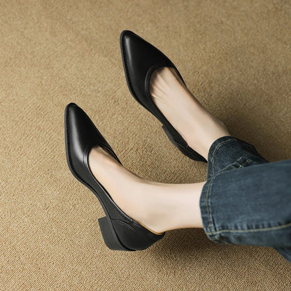 Women's black leather pointed-toe mid-heel pumps worn with cropped jeans on beige carpet, side view.