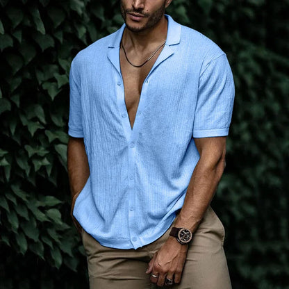 Man wearing light blue short sleeve button-down knit shirt with open collar, paired with khaki pants and a watch.