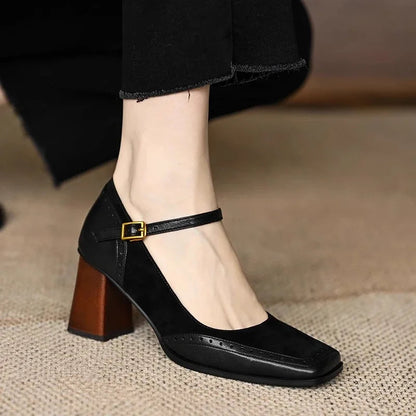 Black women's square toe leather block heel pumps with ankle strap buckle and brogue detailing worn with black trousers