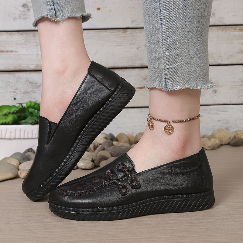 Black leather slip-on loafers for women with decorative floral stitching and platform sole