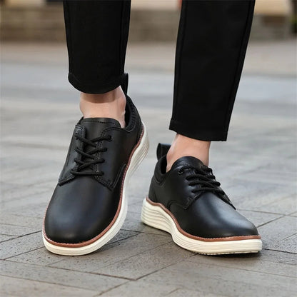 Black leather lace-up casual men's shoes with white chunky sole, worn with black trousers on cobblestone surface