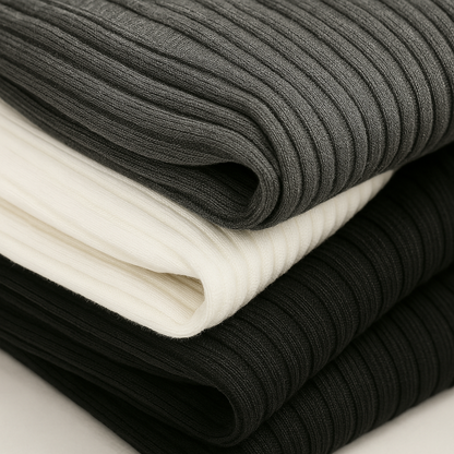 Three folded ribbed knit fabrics stacked in charcoal gray, cream white, and black colorways showing texture detail.